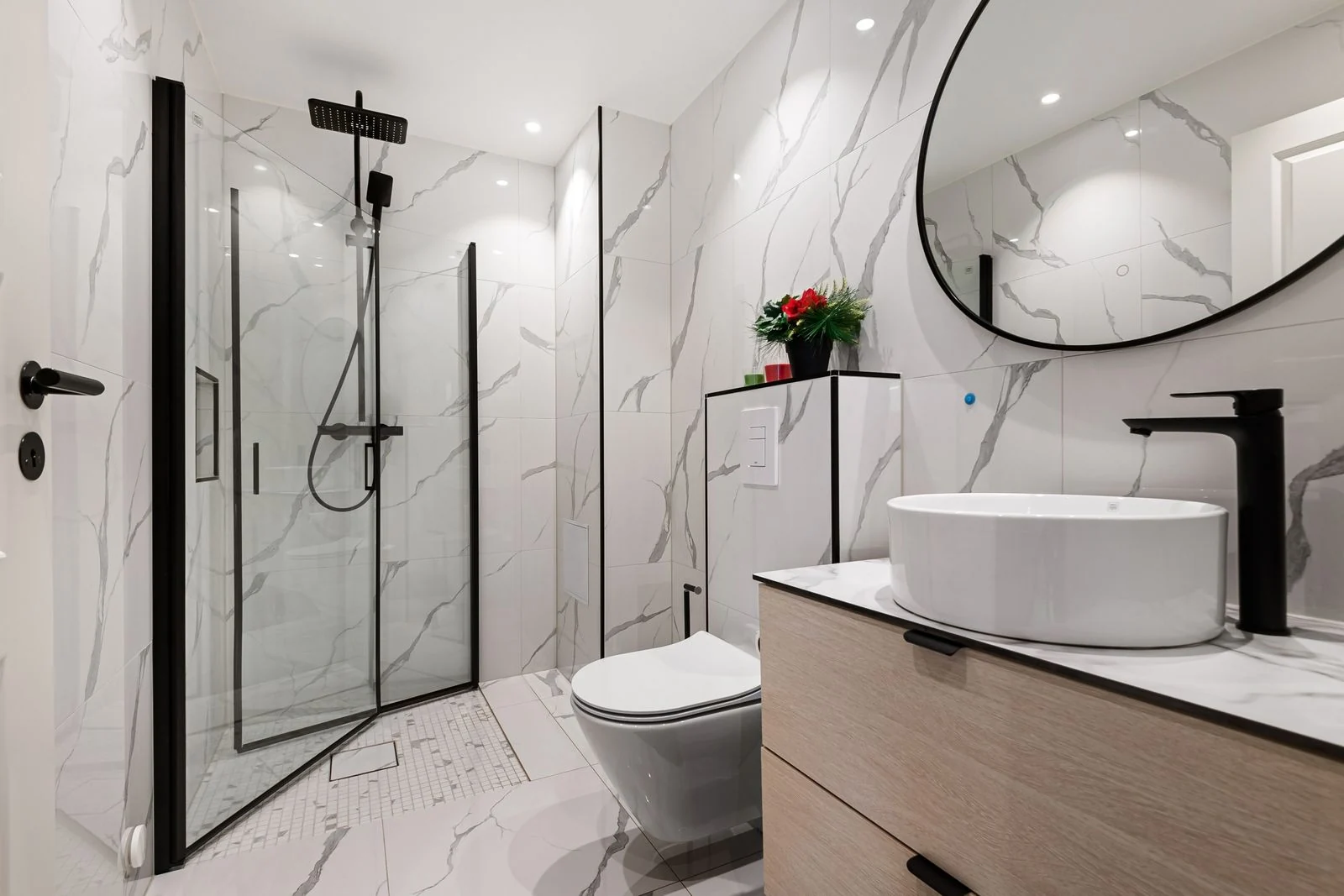 Sleek minimalist bathroom featuring marble walls, black fixtures, and a round mirror