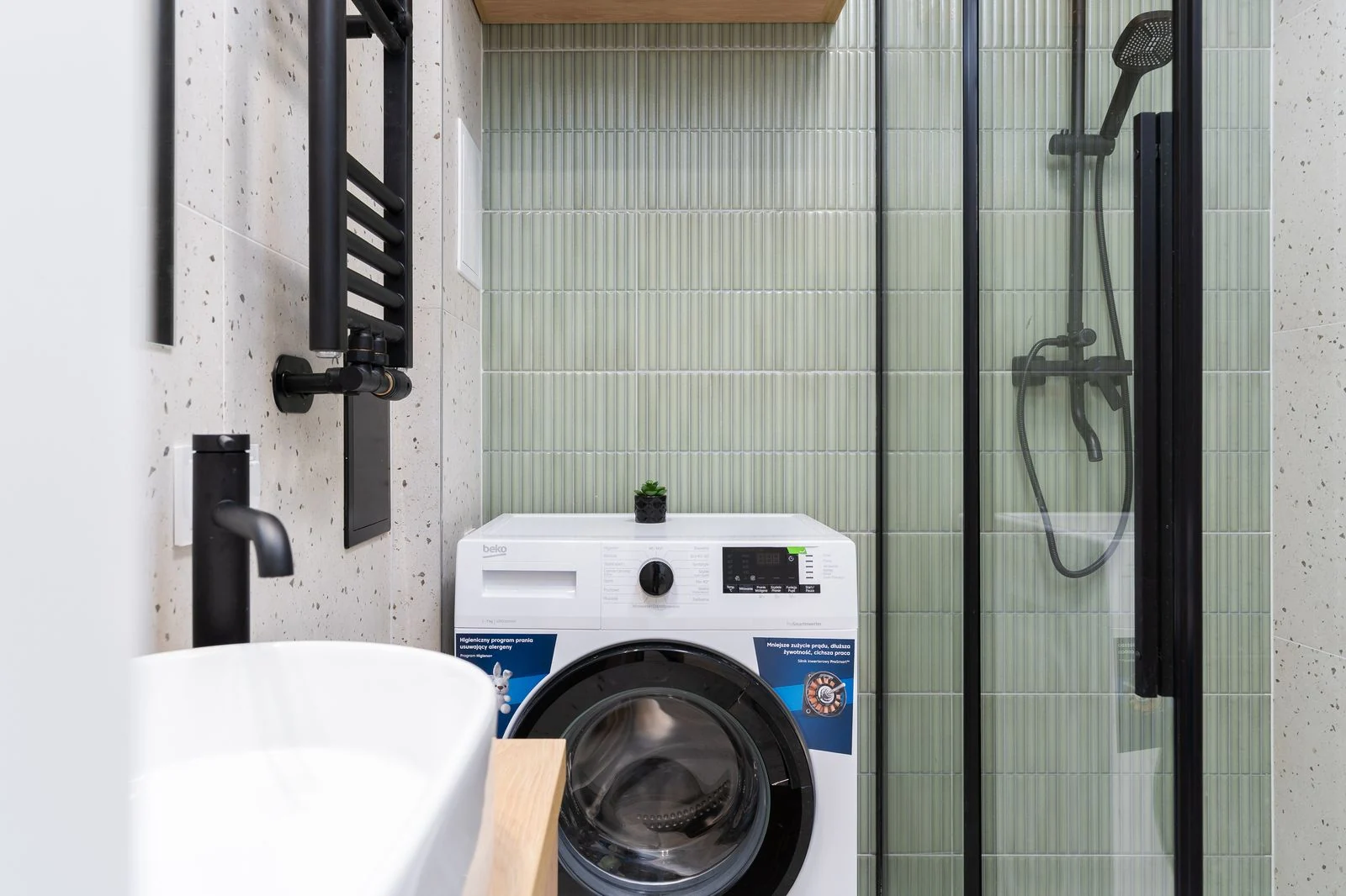 Sleek bathroom design featuring a washing machine, shower, and basin in Kraków