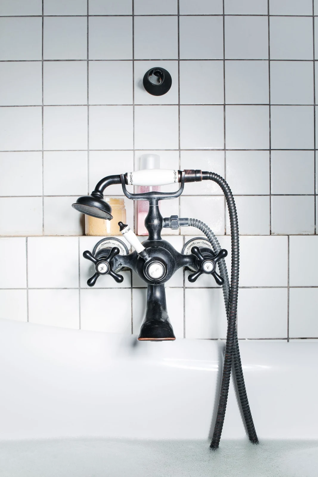 Close-up of a vintage-style bathroom faucet set against a pristine tiled wall