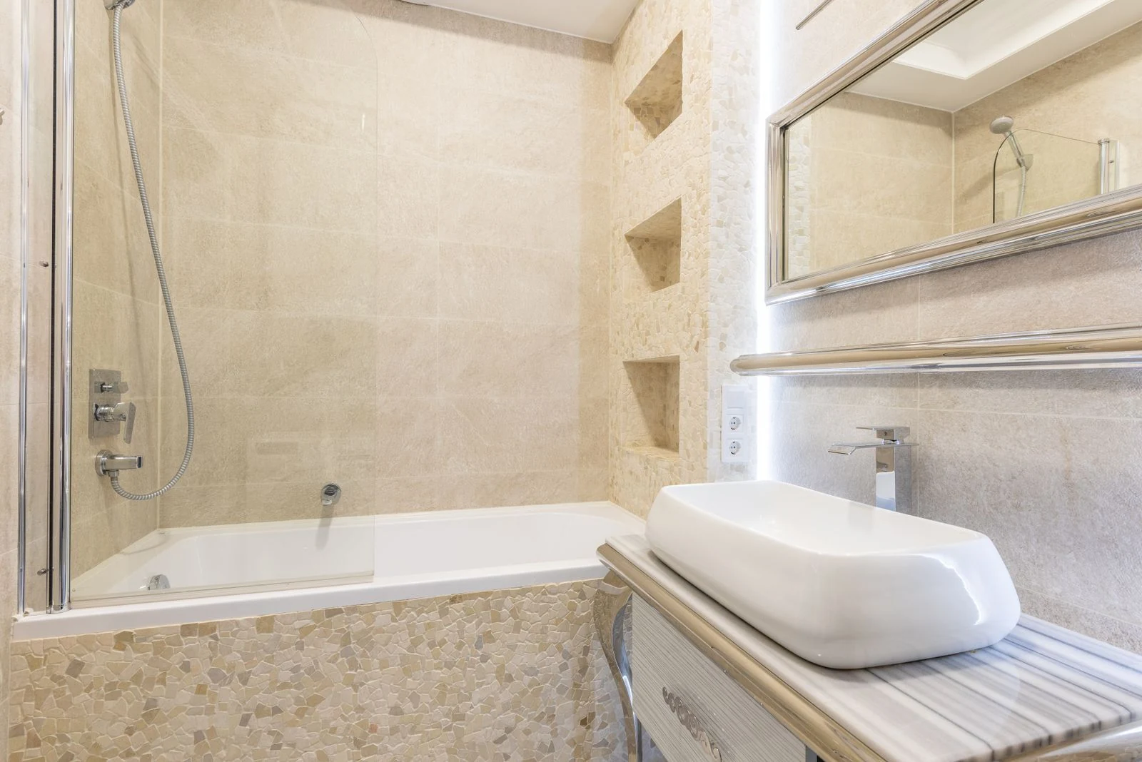 Bathtub against washbasin under rectangular shaped mirror on ceramic wall with shiny light in contemporary house