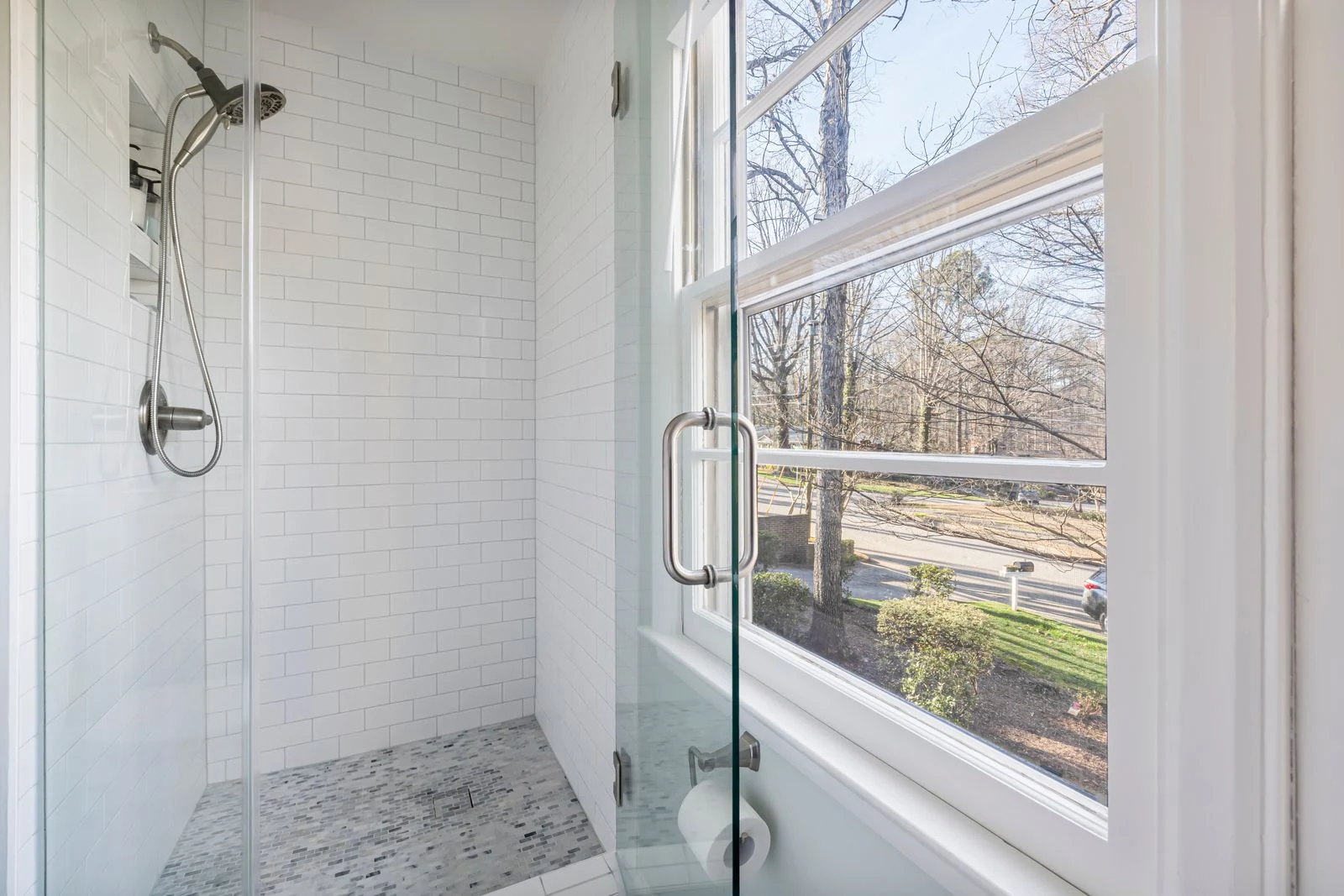 Contemporary bathroom shower with glass door and view of outdoor landscape