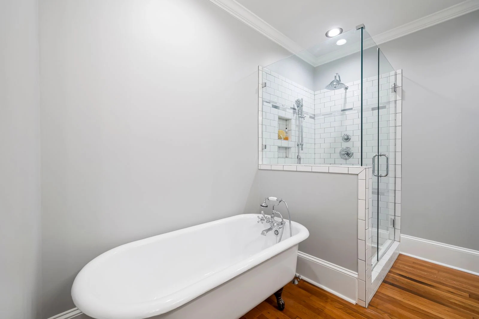 Modern minimalist bathroom featuring a luxurious clawfoot bathtub and a sleek glass-enclosed shower