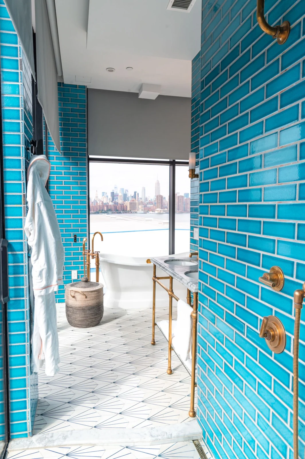 Elegant bathroom with teal tiles and a view of the New York City skyline